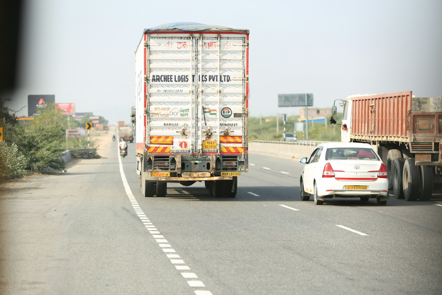 White commercial truck driving on a multi-lane highway.