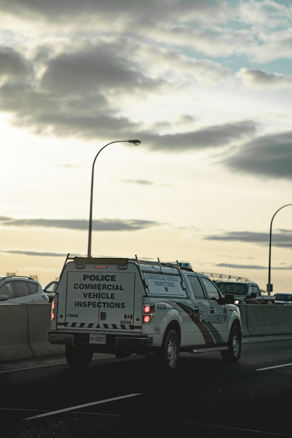 White police inspection truck drives on highway at dusk.